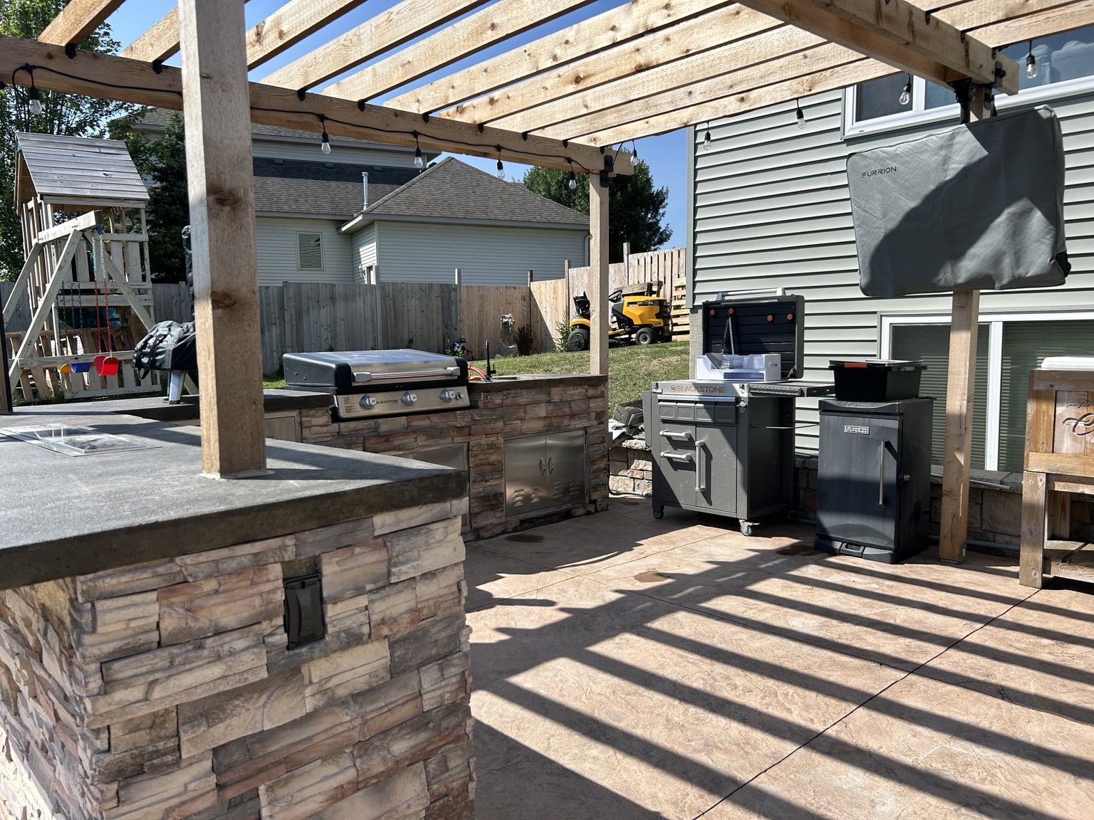Custom outdoor kitchen with stacked-stone island, built-in grill and counters