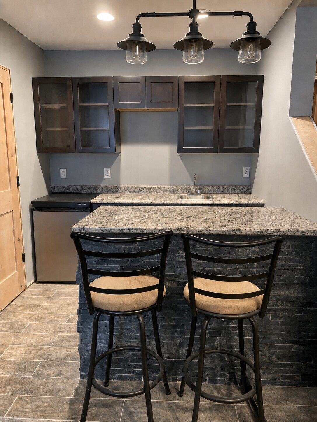 Custom built wet bar with stacked-stone tile and glass cabinetry
